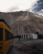 Yellow bus beneath a rugged mountain range, edited with a desaturated Lightroom preset for muted earth tones