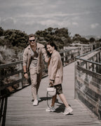 Couple walking along a wooden boardwalk, with subdued greens and muted brown clothing