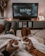 Two people holding whipped coffee drinks during a cosy movie night, edited with a Moody Brown preset