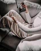 Person reading on a sofa, edited with a Moody Brown preset for muted beige and brown tones