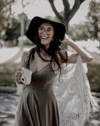 Outdoor portrait of a woman holding an instant camera, with muted greens and earthy brown tones
